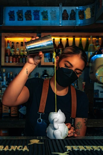a woman wearing a black mask behind her drink