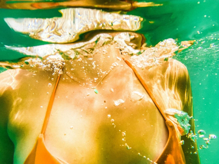 a woman wearing a bikini under water, she is covering her face with hands