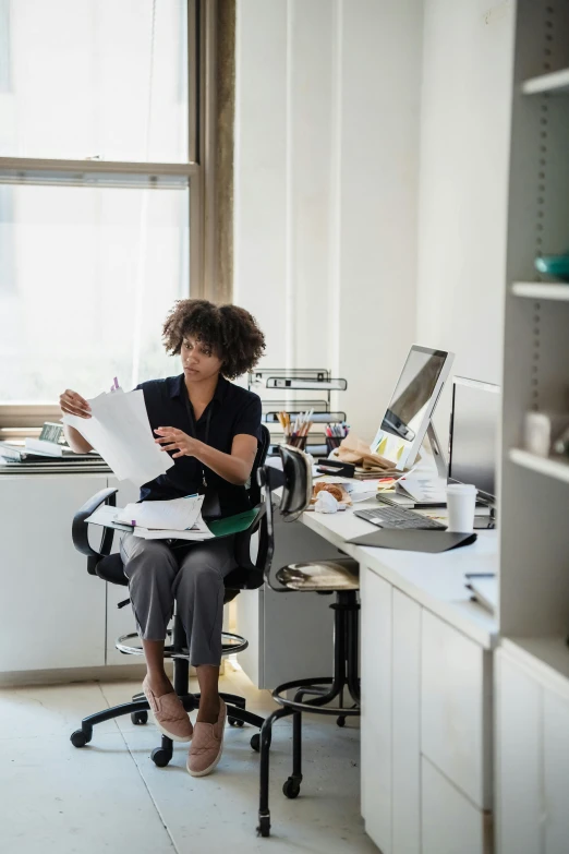 a lady is sitting at a desk with papers