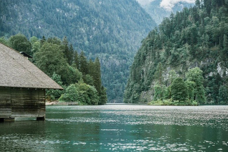 a house is on the edge of the water near some trees