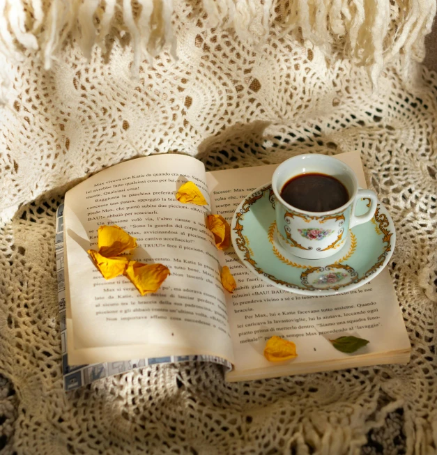 an open book and a cup on a crochet blanket