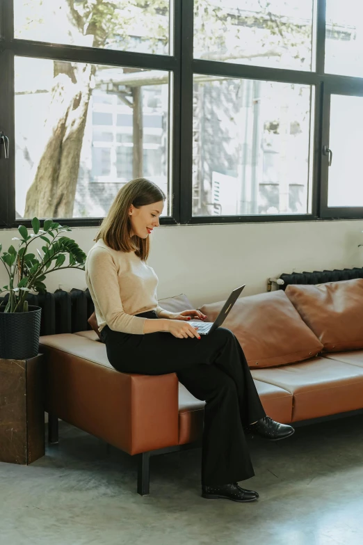 a woman sitting on the couch using her laptop