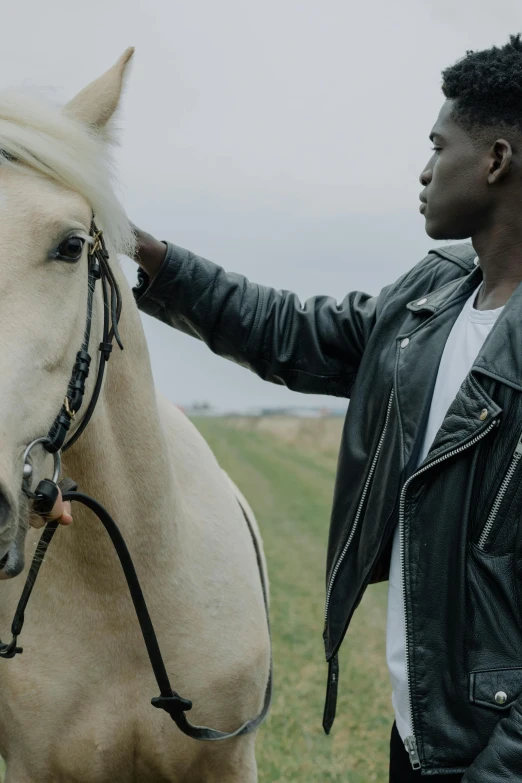 a man in a black jacket next to a white horse