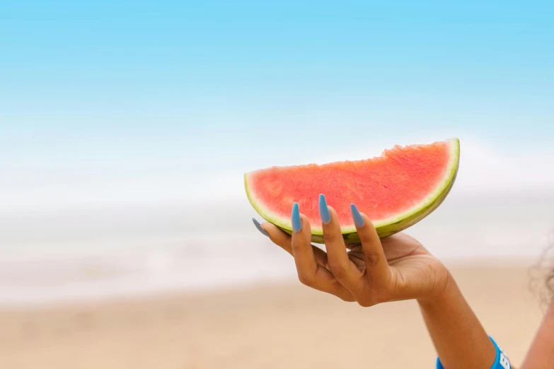 woman in blue nails holds a piece of watermelon