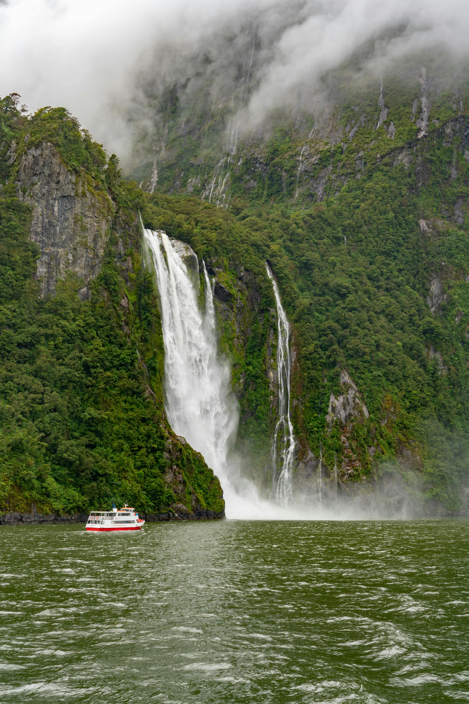 a boat that is in front of a big waterfall