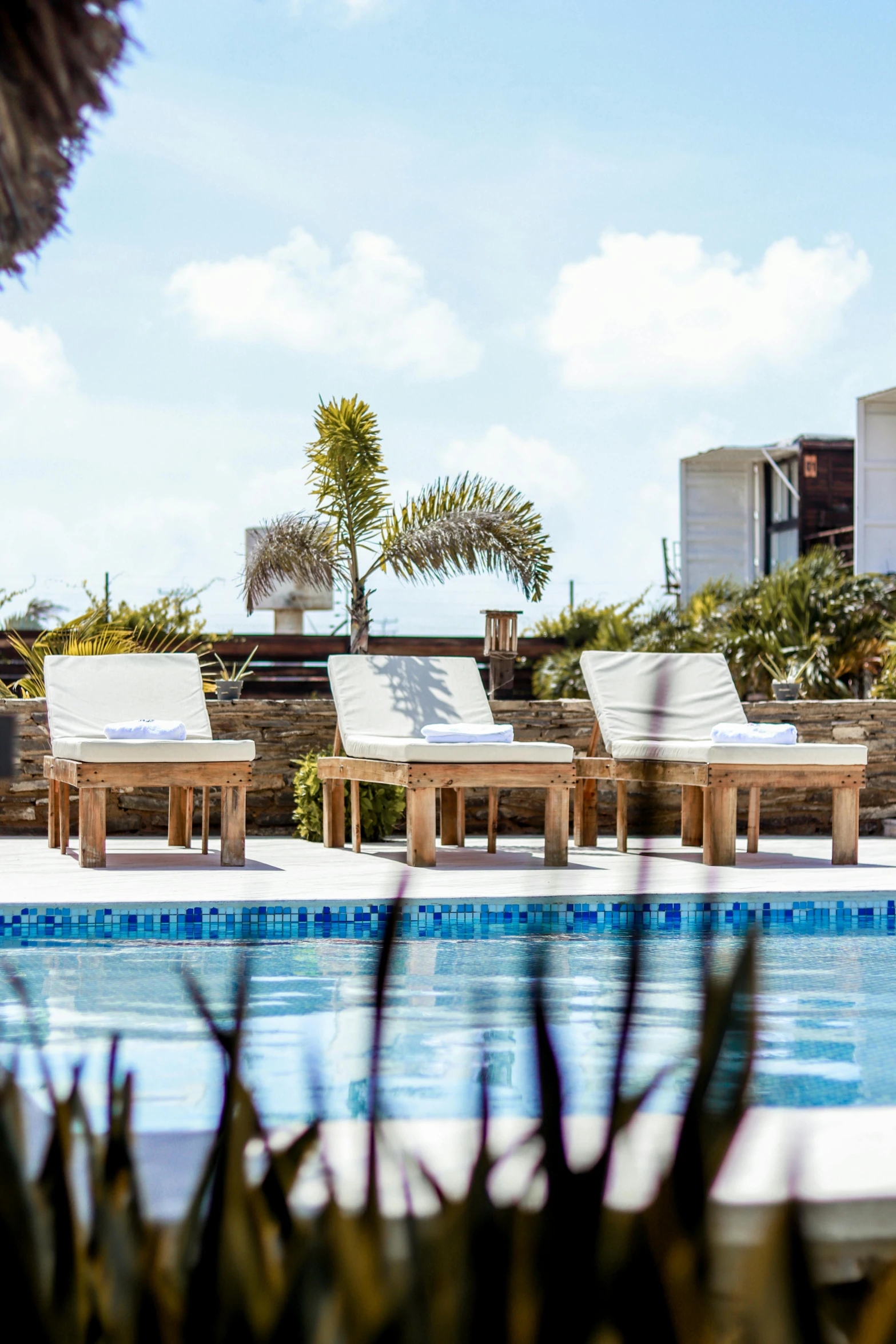 a row of chairs by the pool and in between each of them is a table with four chairs around it