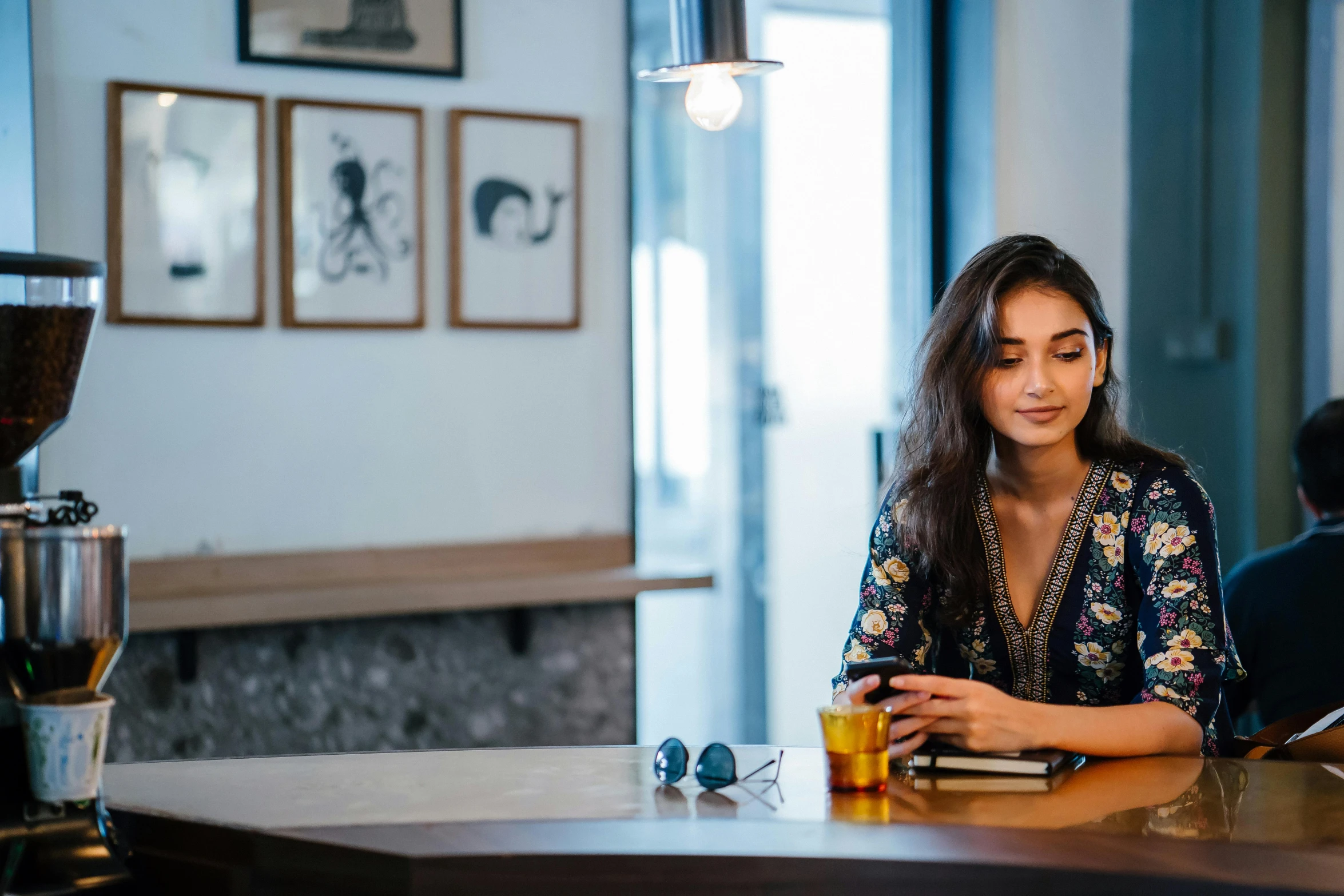 woman drinking coffee while using cell phone at a table