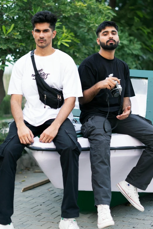 two men sitting on a bench while holding cameras