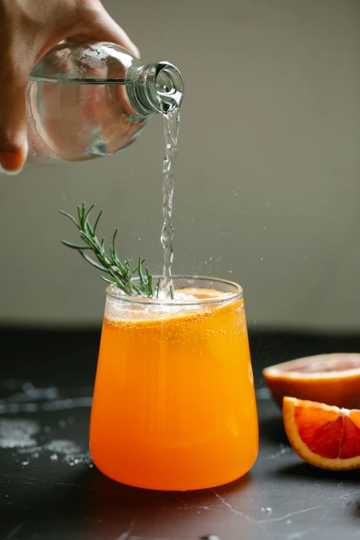 someone sprinkles a rosemary on top of a orange