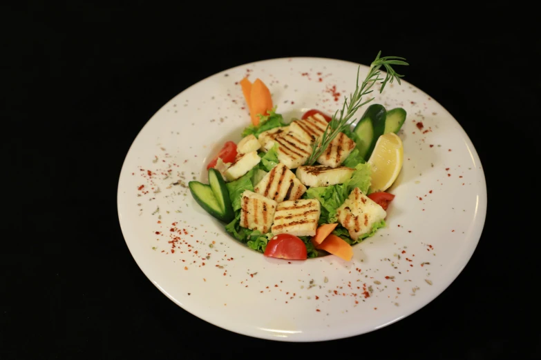 a salad is served in a white plate on a black table