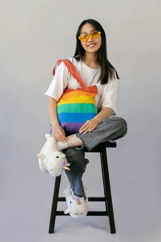 a girl sitting on a stool with two stuffed animals