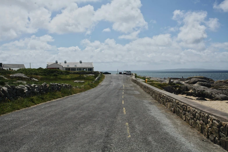 a small white house sits on the side of a gravel road