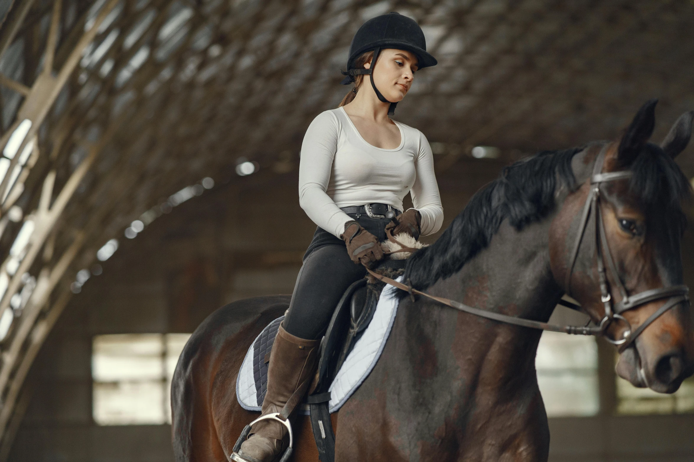 a young woman is riding a horse inside of a barn