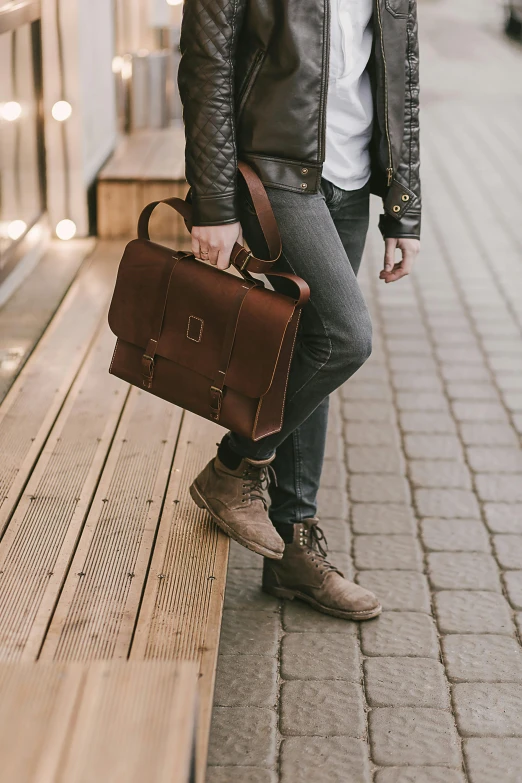 a man wearing black jacket carrying a brown bag