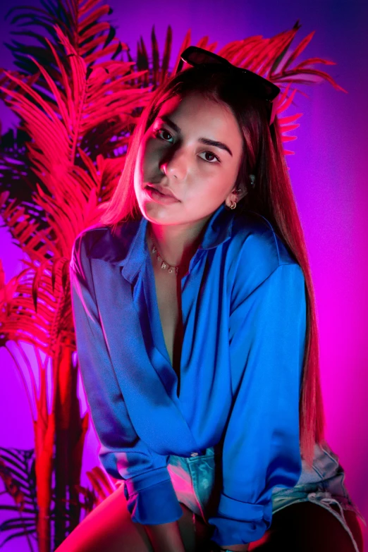 a woman in blue dress sitting against a palm tree