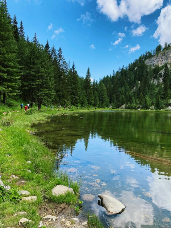 people are walking through the water near some rocks