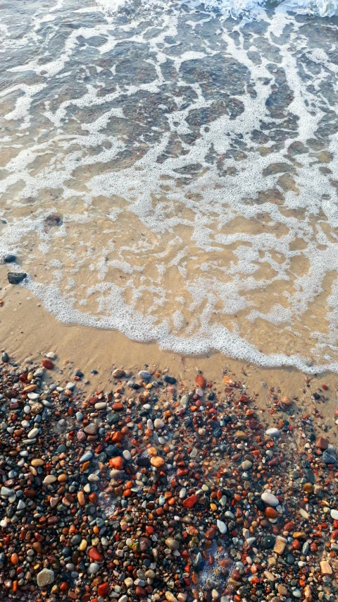 several pebbles and sand on the beach near water