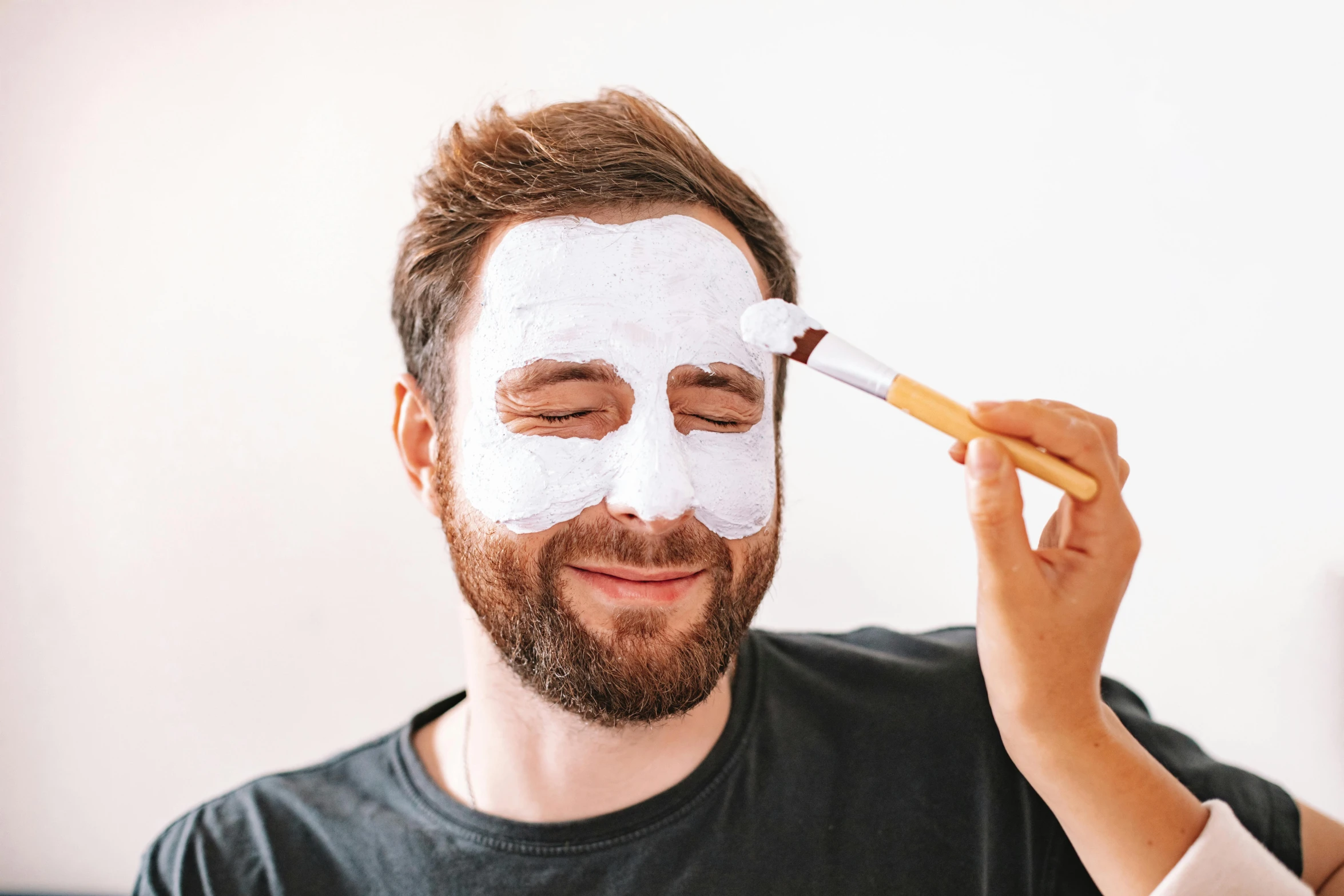 a man is brushing his face with a white mask