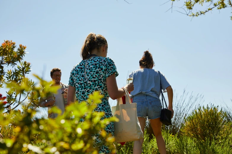 two people carrying totes walking through a field