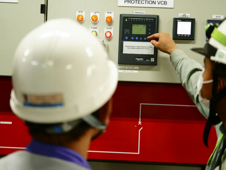 two workers are working on an electrical panel