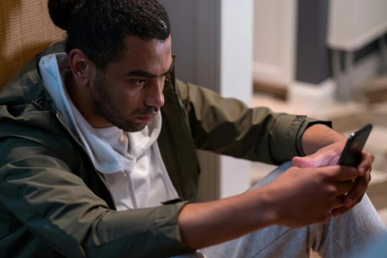 a man looks at his cell phone while sitting down