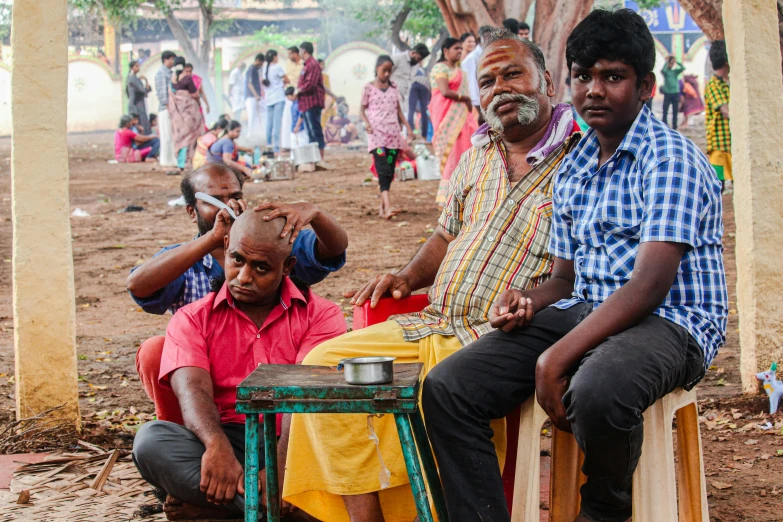 three men sitting at an outdoor table with others