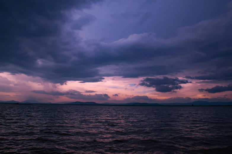 a large body of water with boats under stormy skies