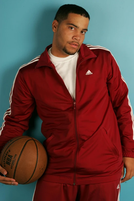 a man holding a basketball wearing a maroon jacket