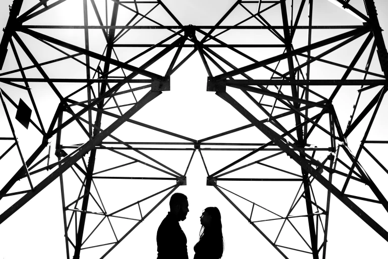 silhouette of couple standing beneath power line with white background