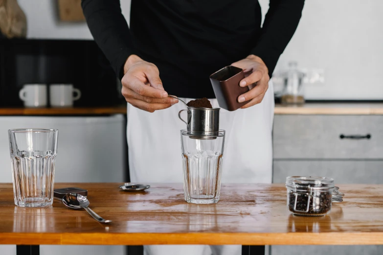 a person in an apron preparing a blender with shakers and measuring cups