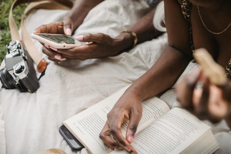 two people looking at a book and touching their phones