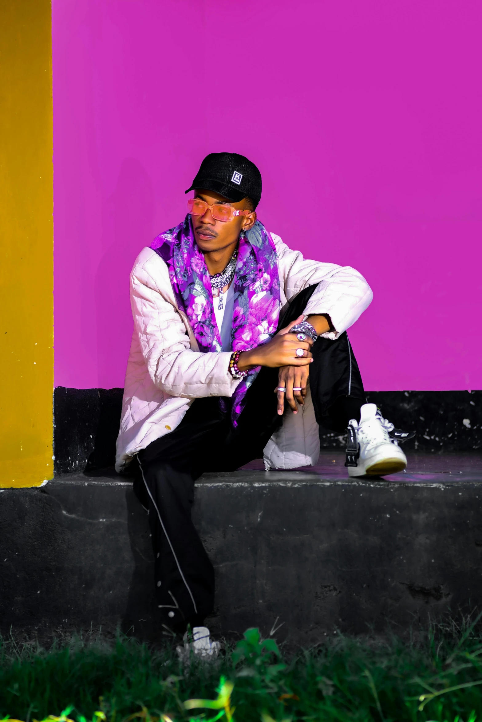 man sitting on concrete in front of a purple and yellow building