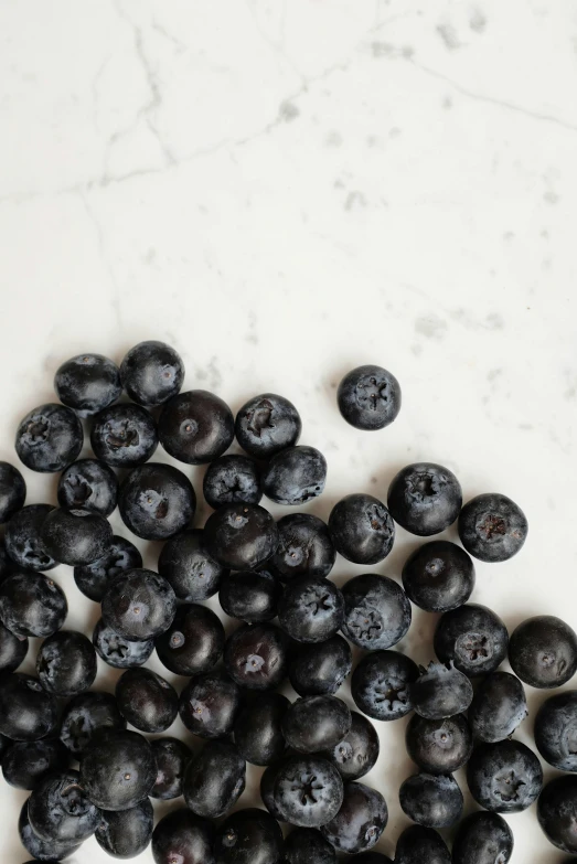 a pile of blueberries next to a spoon