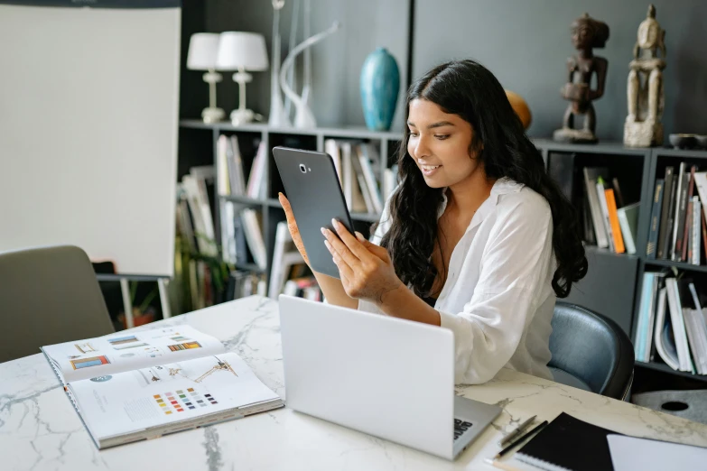 young woman at table looking at screen with tablet in hand