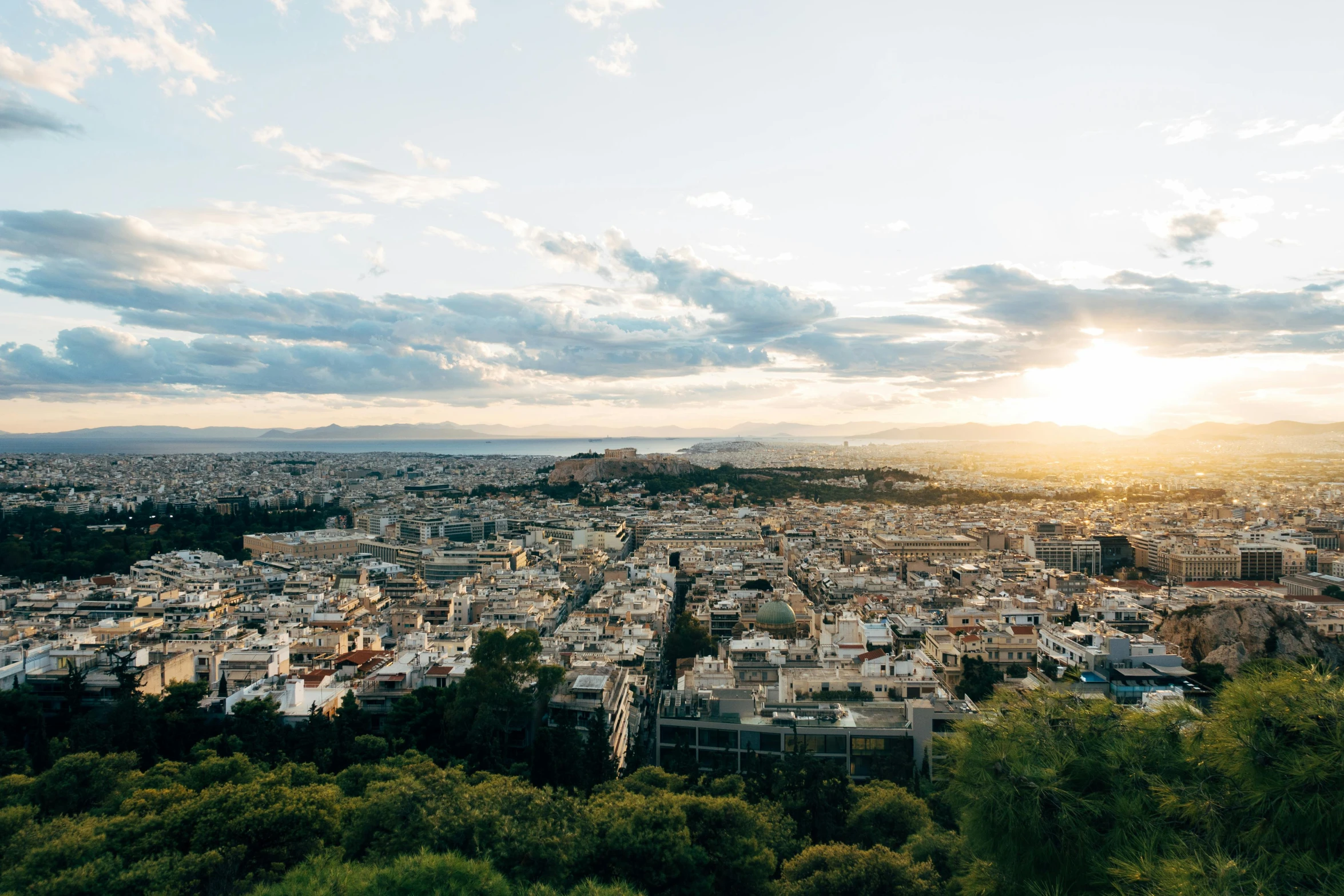 the sun setting over the city with very tall buildings