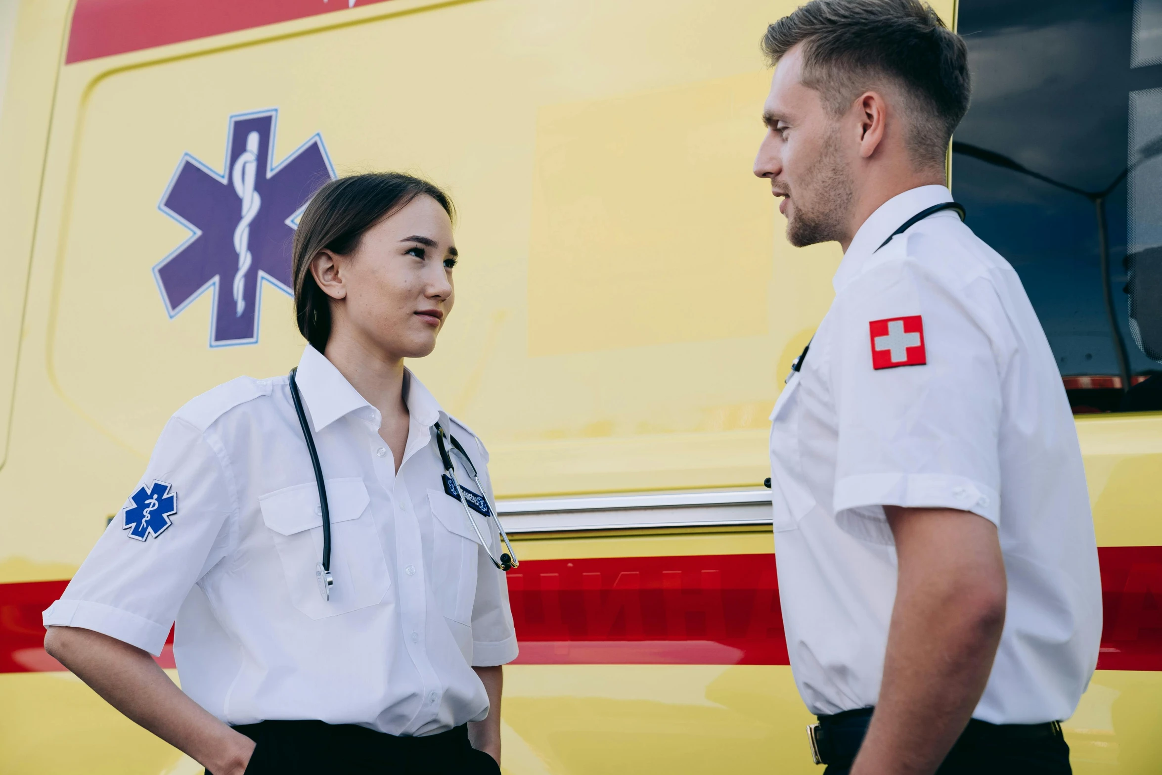 two medical personnel are standing in front of a yellow truck