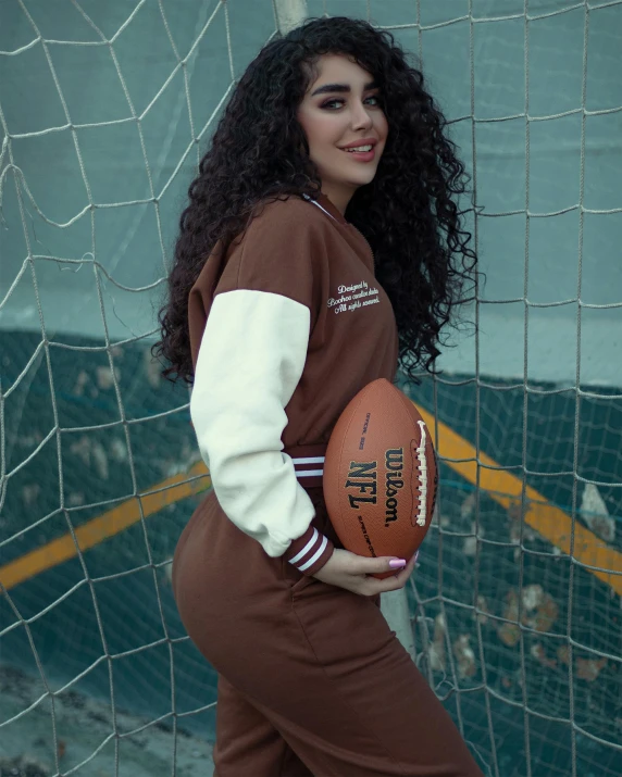 a woman is posing with an american football