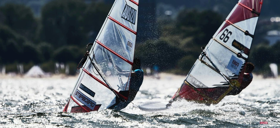 two people on sailboards riding on the water