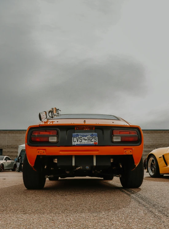 a very pretty orange car parked in a lot