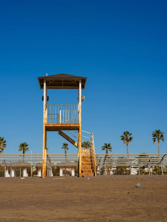 a tower with stairs on top is standing on the sandy beach