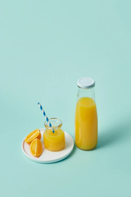 an orange juice with straw and two pieces of orange