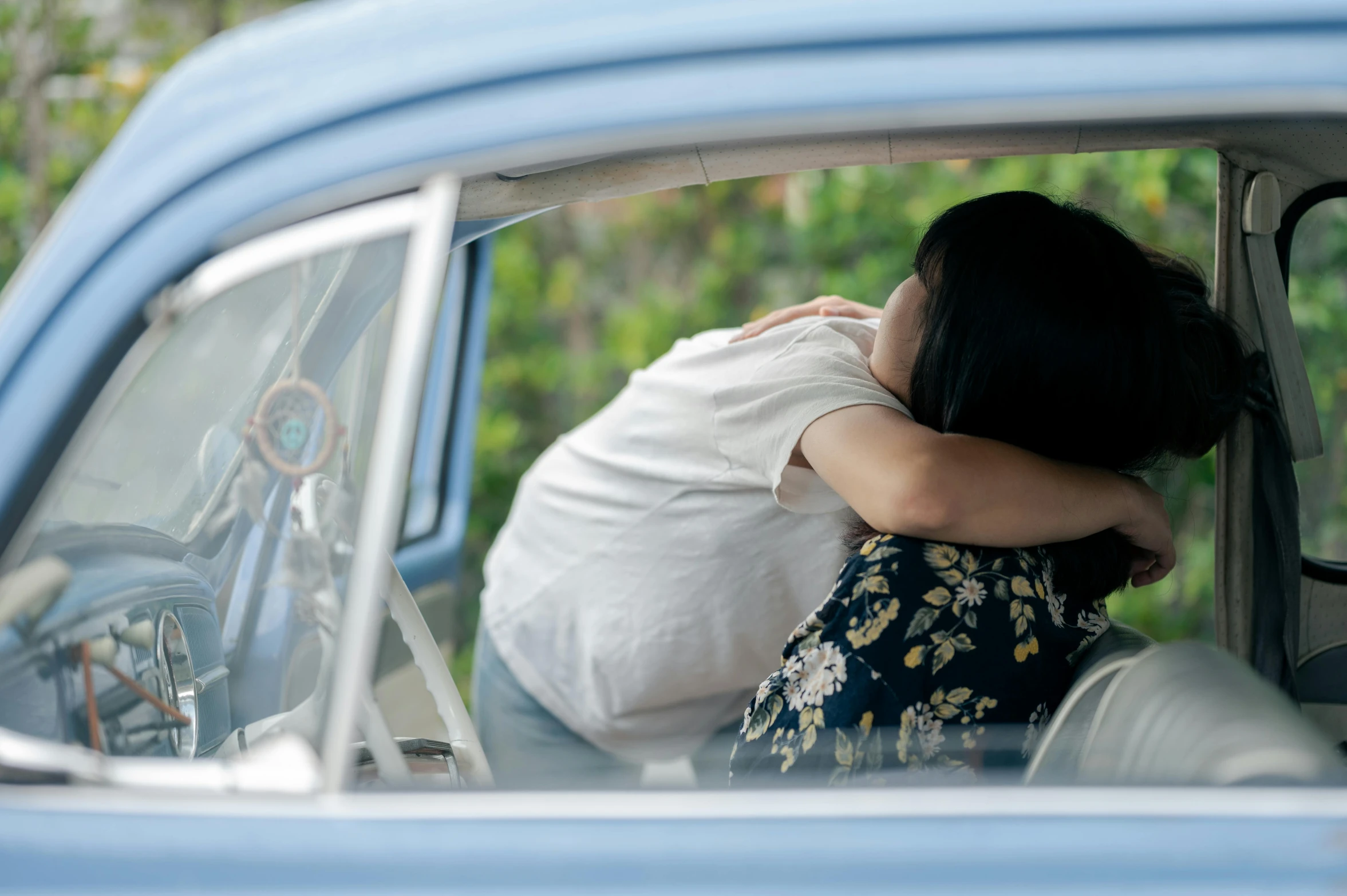 a woman in white shirt leaning against a car door