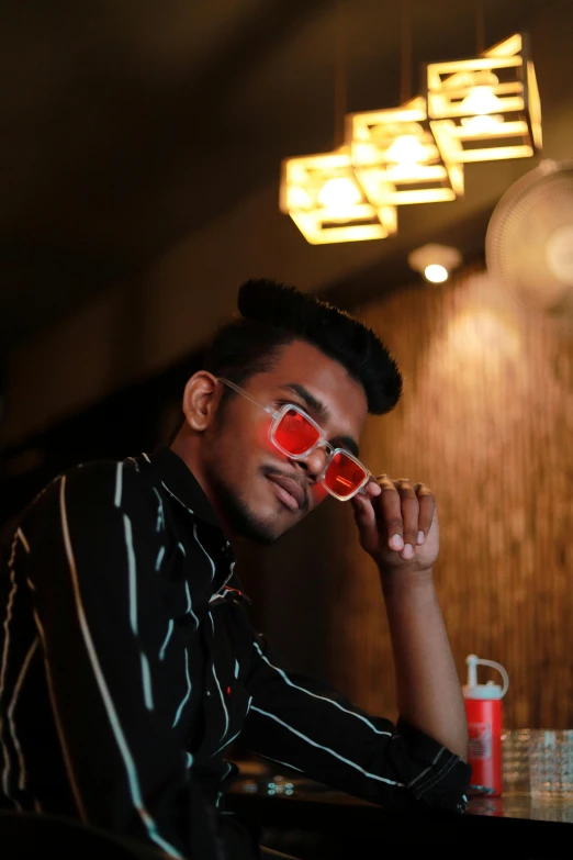 a man sitting at a table with food and red sunglasses on