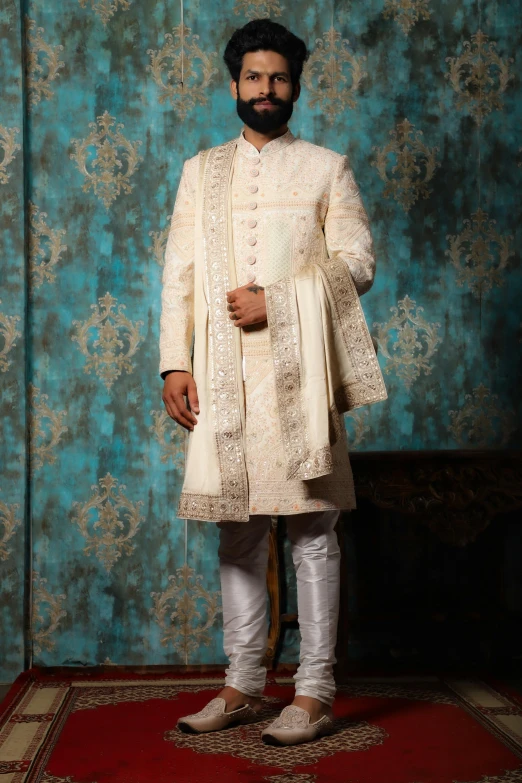 a man wearing an embroidered white outfit with long hair and mustache