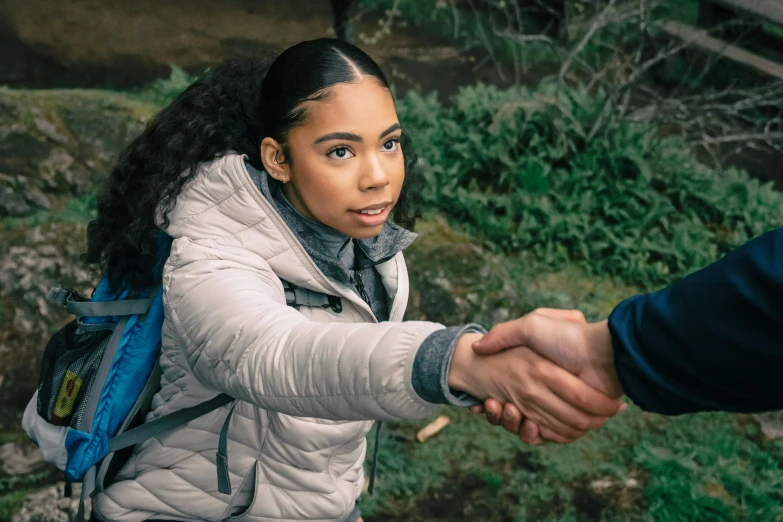 a woman in white jacket shaking hands with man