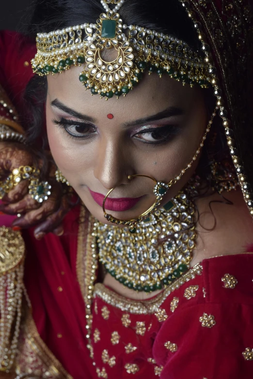 a woman wearing a red and gold veil and bridal jewelry