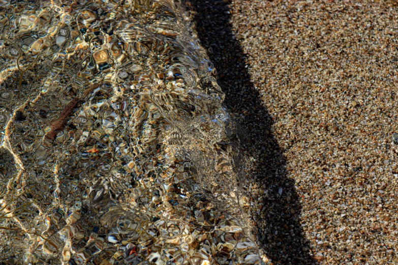 the beach floor with little bubbles of water in the sand