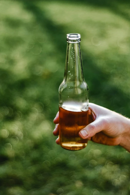 a hand holding a beer bottle in a blurry po