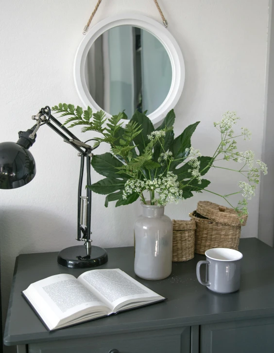 a desk with a vase with flowers and a book