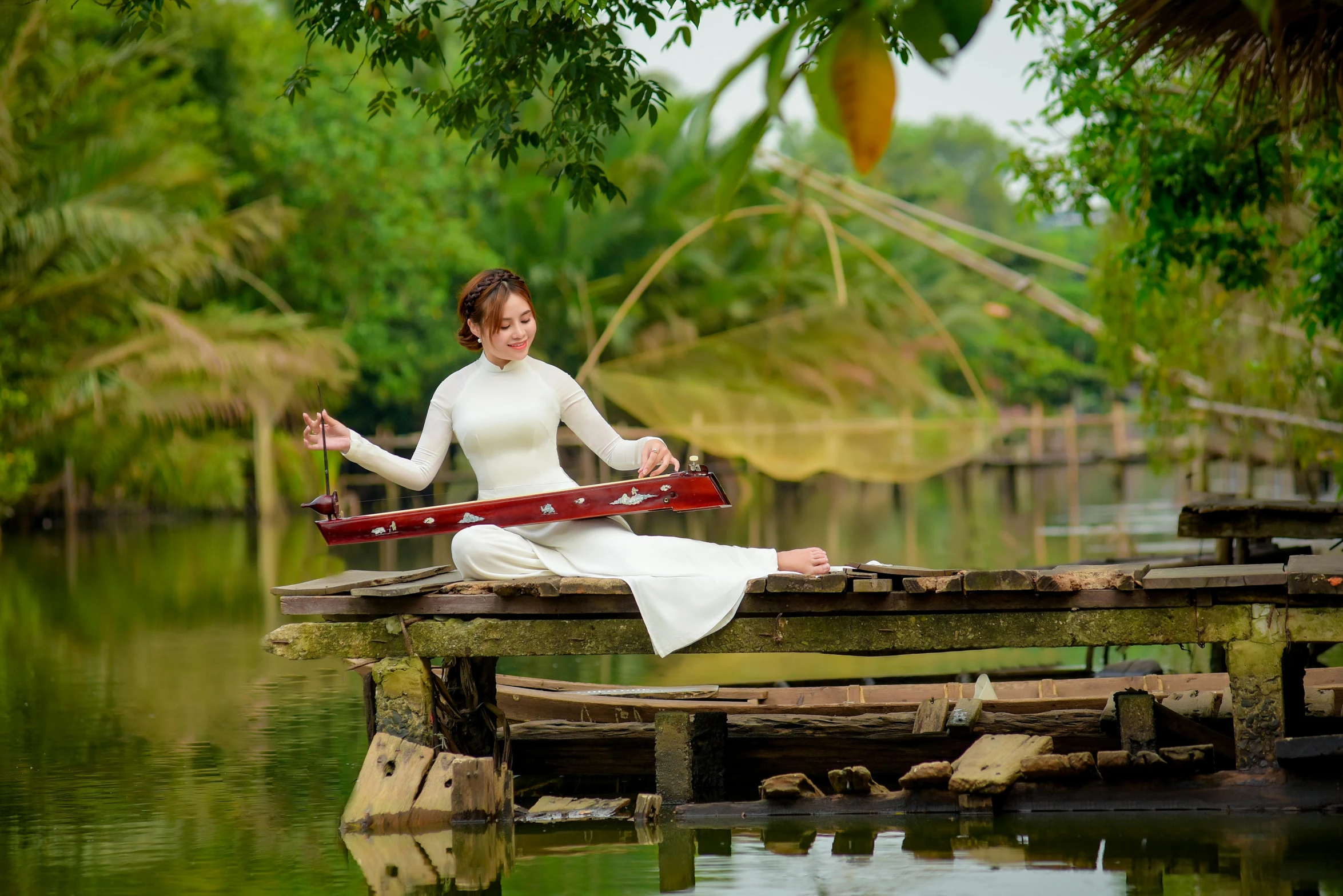 a woman sitting on a piece of wooden pier with her arms crossed and leg in yoga position, stretching